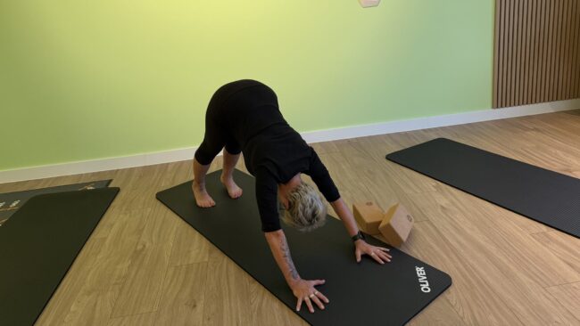 Yoga Kursteilnehmerin in der Yoga-Position "herabschauender Hund"